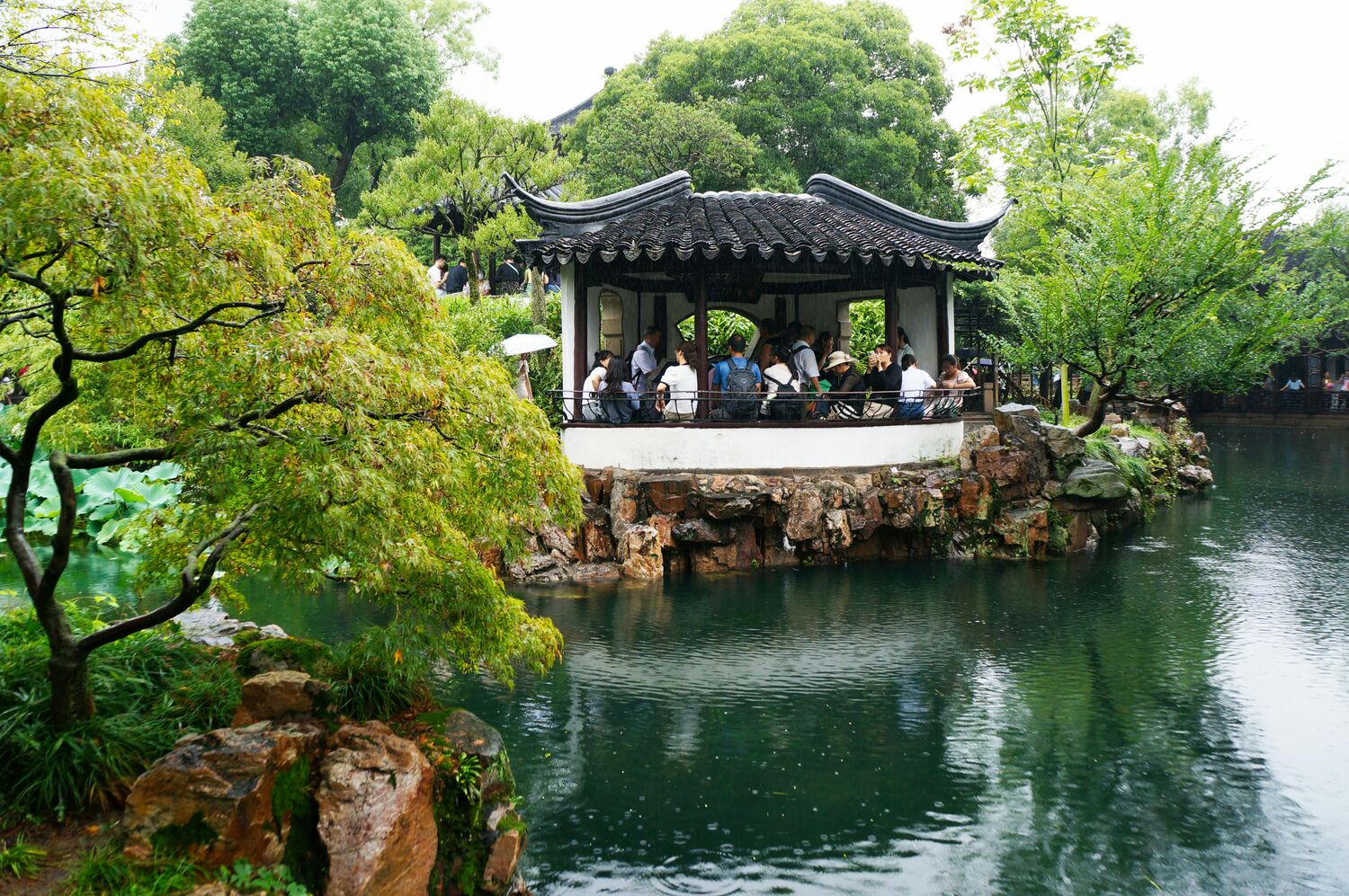 Paisaje de jardín chino con puente y pabellón sobre el agua