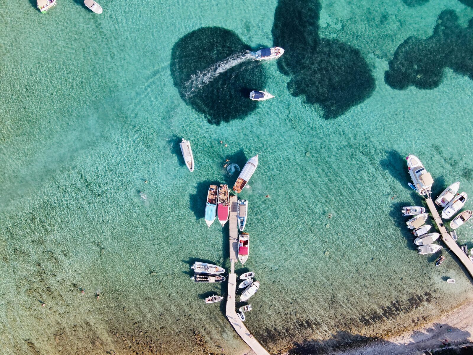 Marina de barcos sobre agua turquesa vista desde el aire