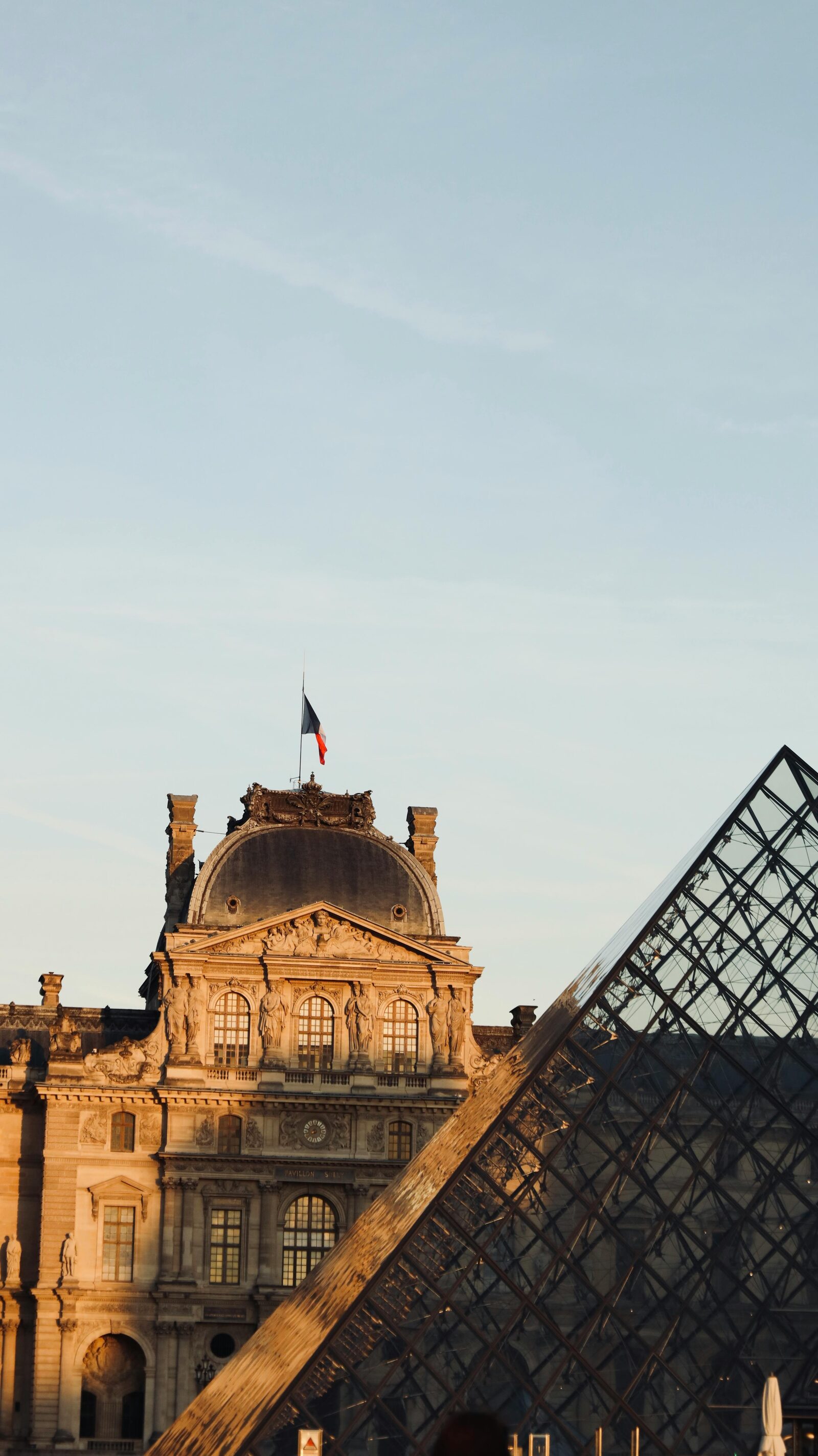 The Louvre Pyramid with the French flag · Paris