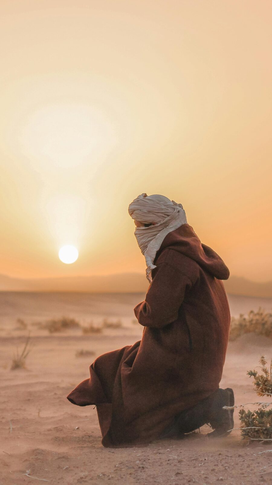 Lone walker on the desert dunes at sunset